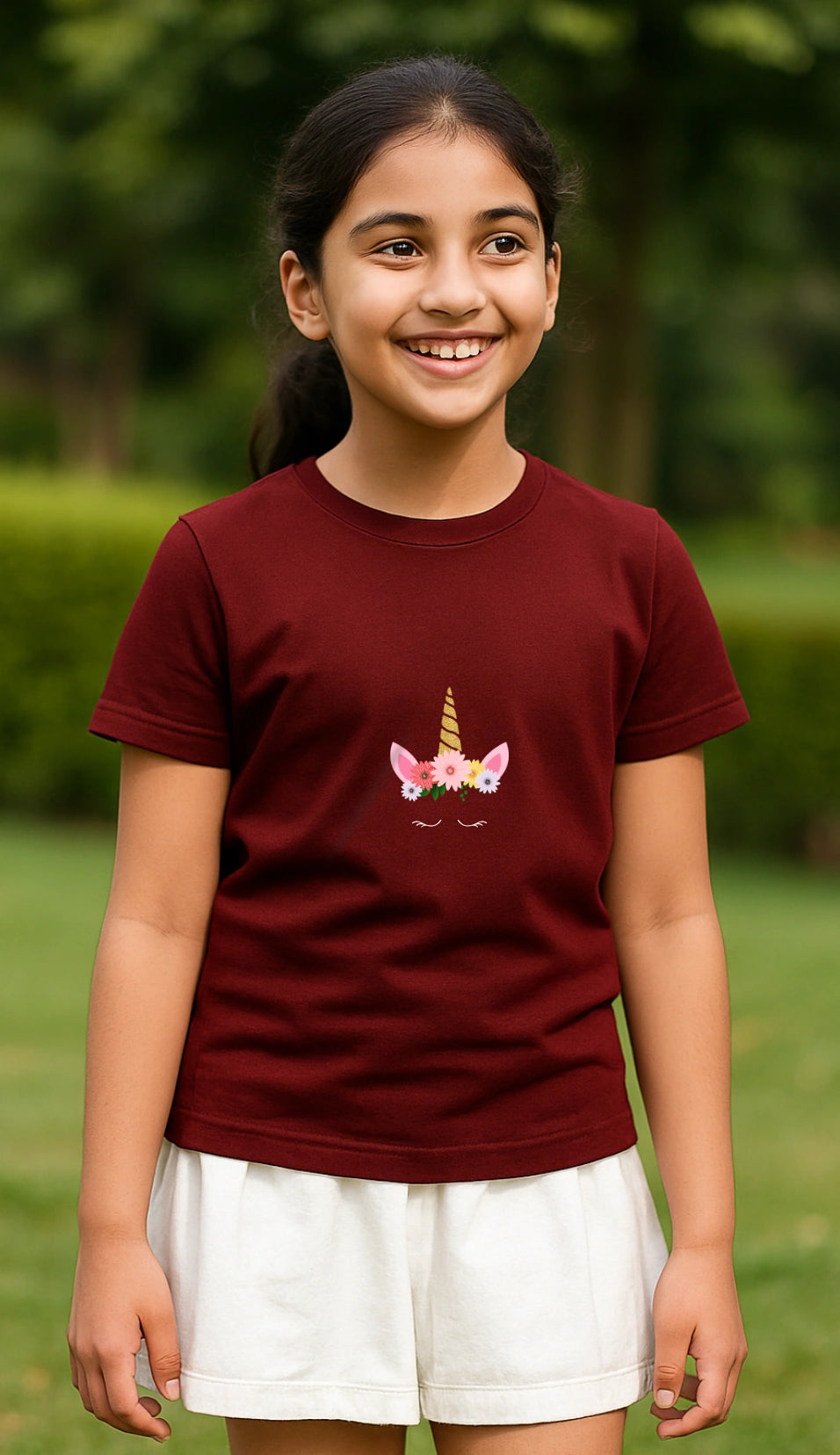 Young girl wearing a maroon t-shirt with a pony crown design outdoors.