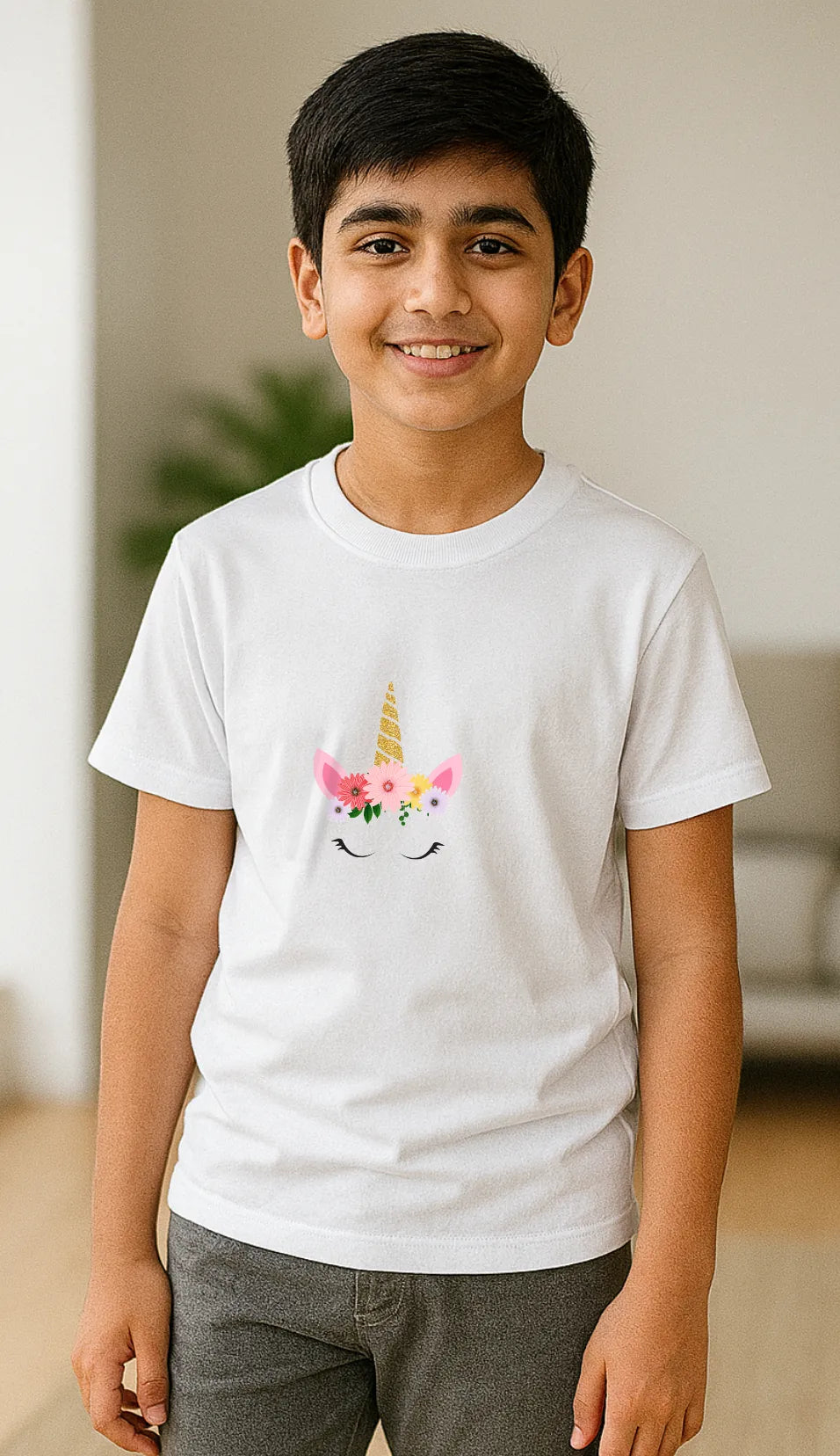 Young boy wearing a white t-shirt with a unicorn flower crown design, standing indoors.