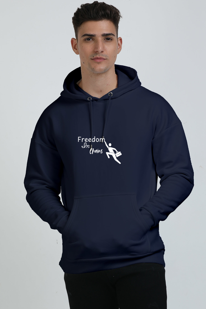 A man wearing a Navy Blue unisex oversized hoodie with the text 'FREEDOM IN CHAINS' with a man toucing the letter "m"printed on the front.