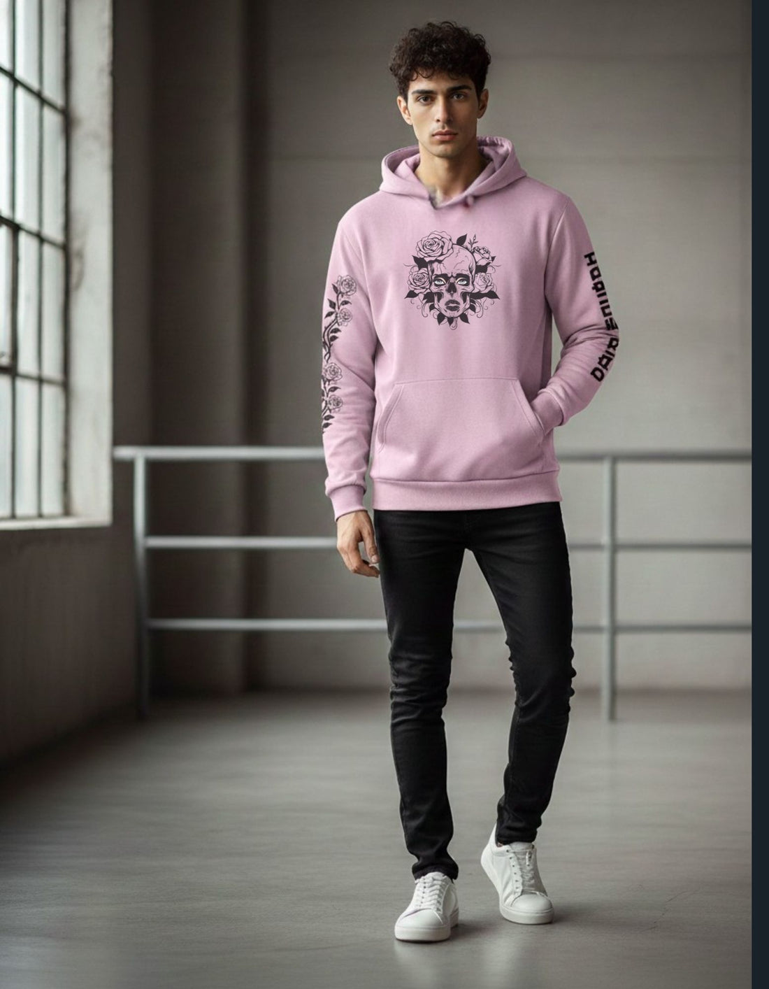 Person wearing a pink hoodie with a graphic design in a minimalistic indoor setting