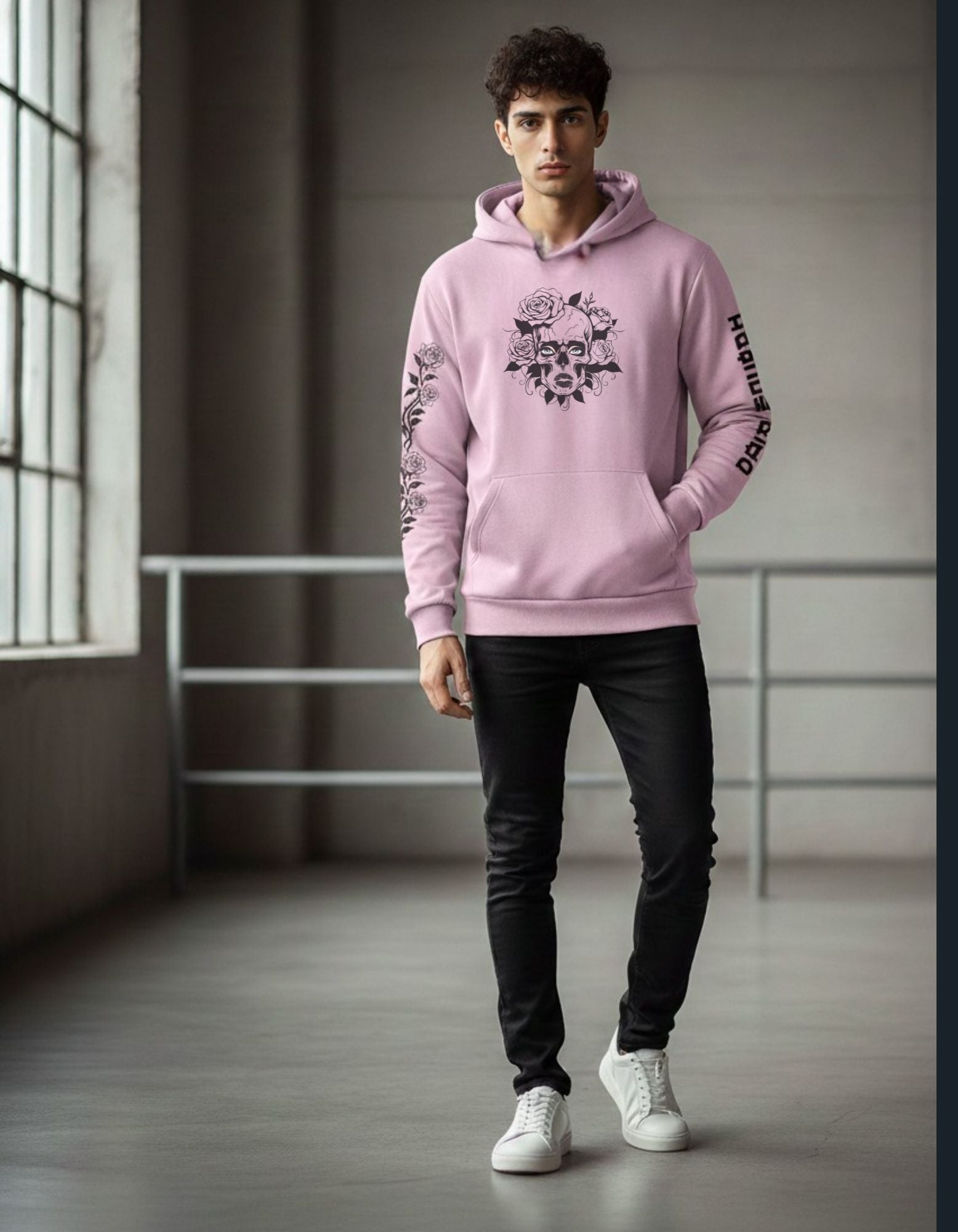 Person wearing a pink hoodie with a graphic design in a minimalistic indoor setting