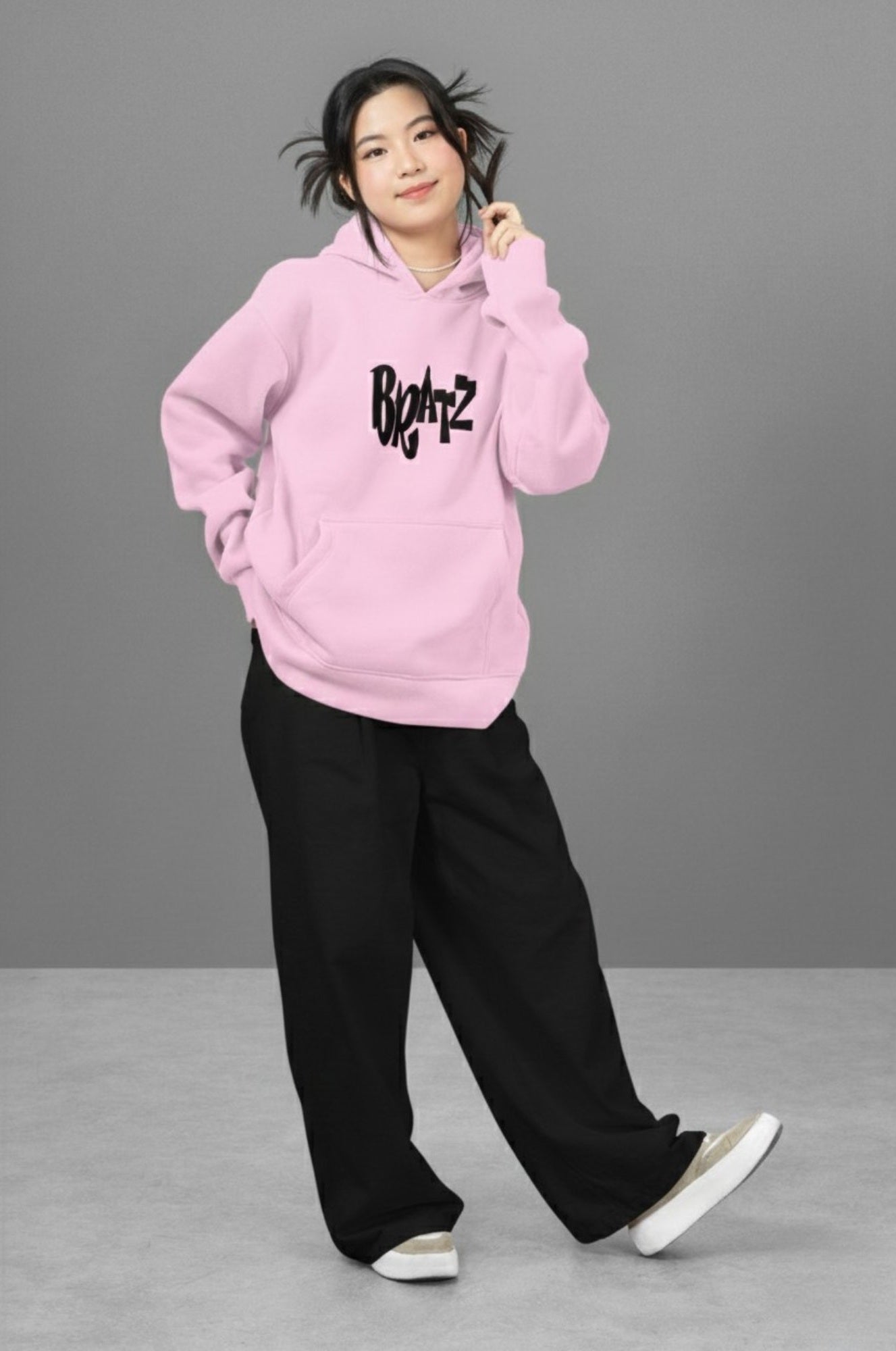 Woman models Light Pink Hoodie. with mischief related graphic in black and regular fit. 320 GSM fleece.