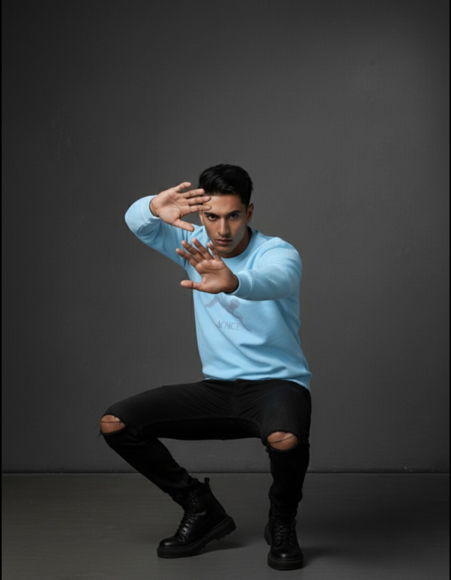 Man in Baby Blue 320 GSM Sweatshirt, squatting with hands up. Unisex crew neck with Balance Graphic chest print.