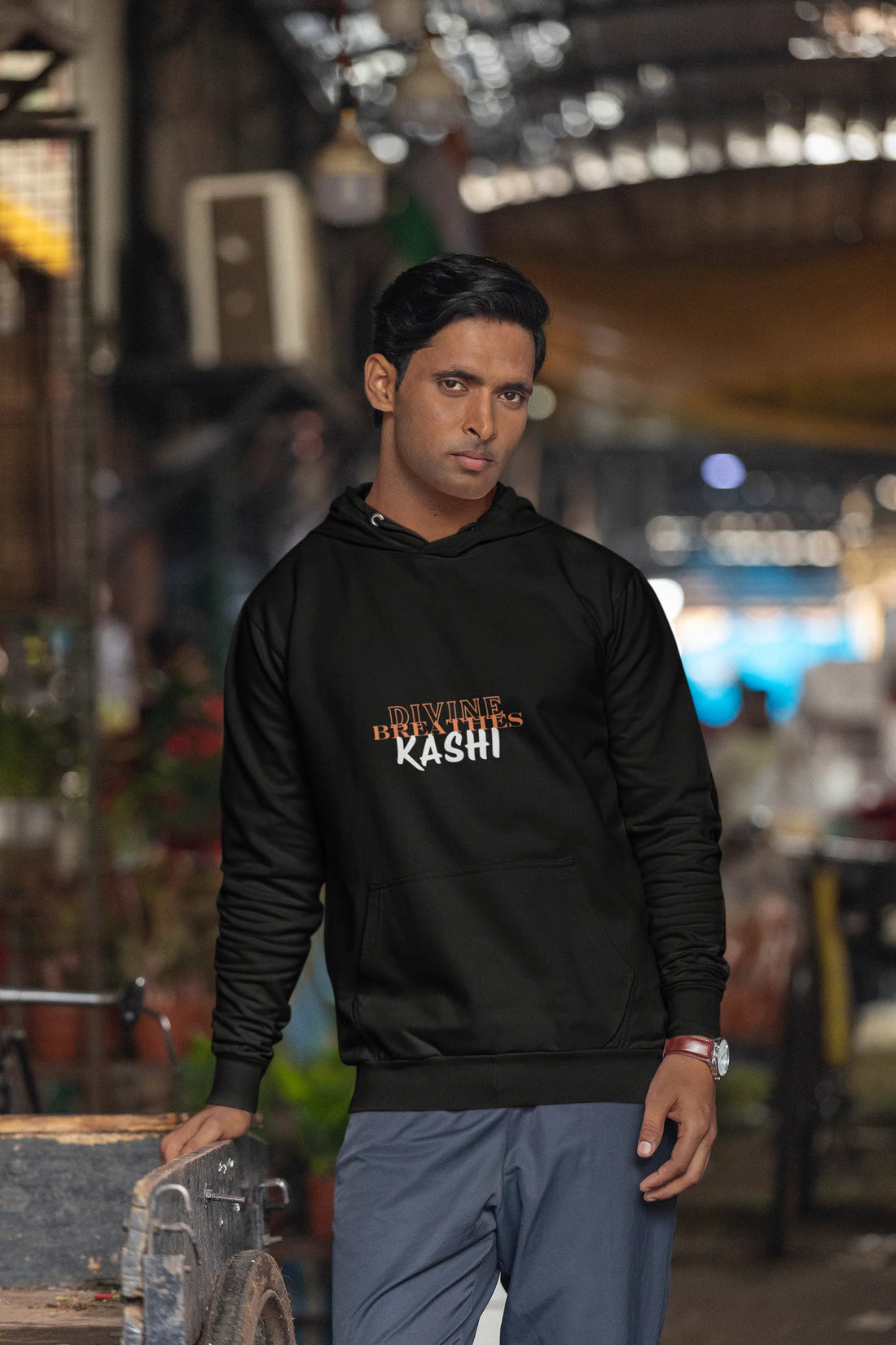 Man wearing a Black hoodie with text "DIVINE BREATHE KASHI", standing in an Antique Store.